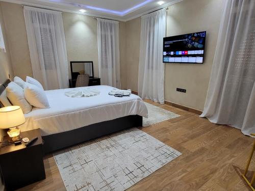 a bedroom with a bed and a tv on a wall at Villa Marrakech Rimass - 6 Chambres Dont 5 Suites Luxe, Piscine Privee & Jardins in Marrakech