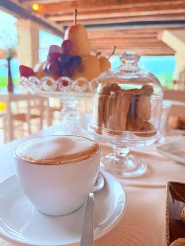 a cup of coffee sitting on a table with a plate at Asolo Norah's Hill Agri Rooms in Caenere