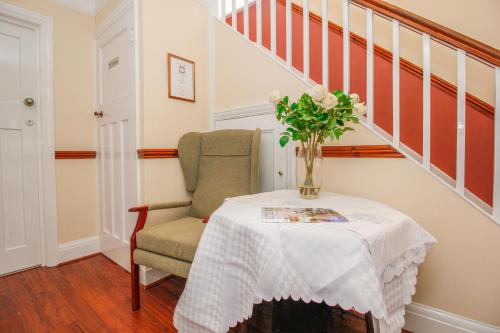 a table with a vase of flowers and a chair at Harris Guest Accommodation in Oxford