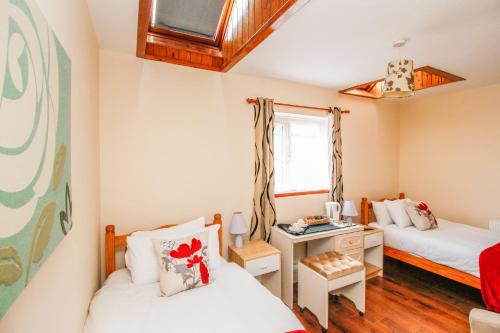 a small room with two beds and a desk at Harris Guest Accommodation in Oxford