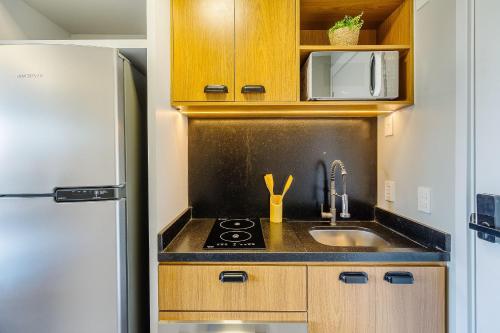 a small kitchen with a sink and a refrigerator at Novíssimo - Skyline Parque Moinhos in Porto Alegre