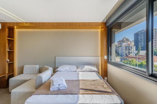a bedroom with a bed and a large window at Novíssimo - Skyline Parque Moinhos in Porto Alegre