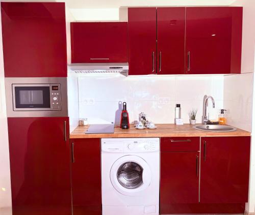 a kitchen with red cabinets and a washing machine at Appart'hôtel - Seclin-Appartements in Seclin