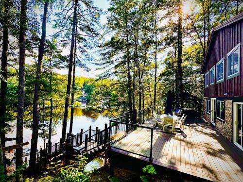 a house with a deck next to a lake at Lakefront Home-Stunning Views-Hot Tub, 3100 sqft! in Wakefield
