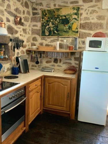 une cuisine avec des armoires en bois et un réfrigérateur blanc dans l'établissement Maison D'Augusta, à Mayrinhac-Lentour