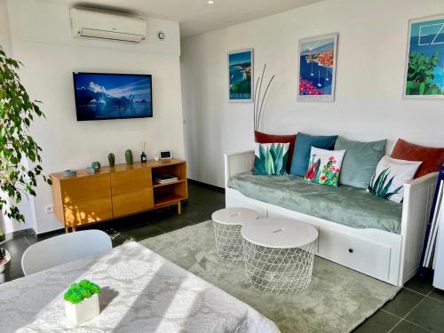 un salon avec un canapé et une table dans l'établissement Terrasse, vue mer & montagne, parking & clim, à Nice