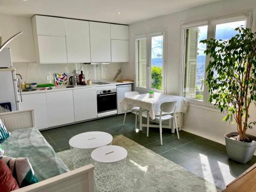 une cuisine avec des armoires blanches et une table dans une pièce dans l'établissement Terrasse, vue mer & montagne, parking & clim, à Nice