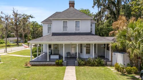 a white house with a porch and a lawn at Martin B- historic district apt with pool in Ocala