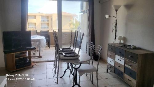 une pièce avec une table, des chaises et une fenêtre dans l'établissement appartement bord de Mer, à Santa-Lucia-di-Moriani