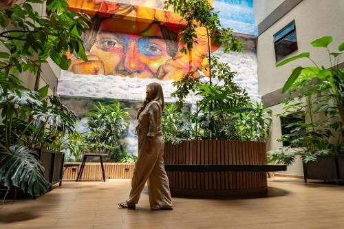a woman walking in front of a painting of a woman at Los Patios Cool Living in Medellín