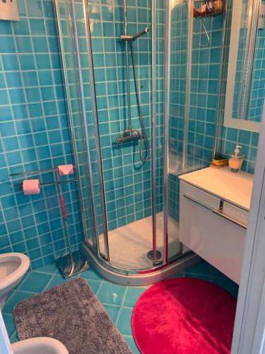 une salle de bain carrelée bleue avec une douche et un tapis rouge dans l'établissement Studio in cannes Croisette, à Cannes