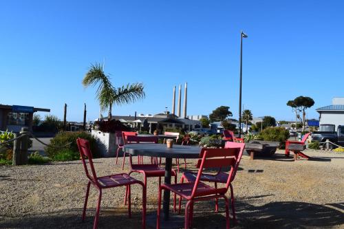 a group of red chairs around a table in a yard at The Landing at Morro Bay in Morro Bay