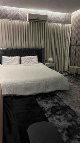 une chambre avec un grand lit avec des draps blancs dans l'établissement شقه انيقة بغرفه وصاله مدخل خاص, à ‘Aryam