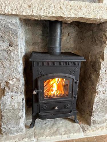 a black stove in a stone fireplace at Ana & Angelo House Vuno Himare in Vuno
