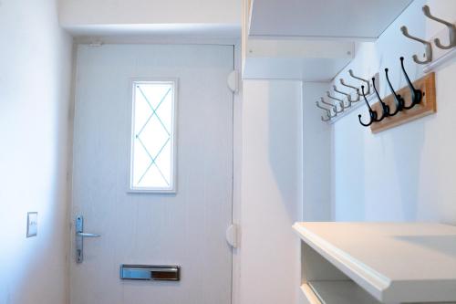a bathroom with a white door and a window at Cleave House - Chic & Stylish 3 bed house in Farnborough