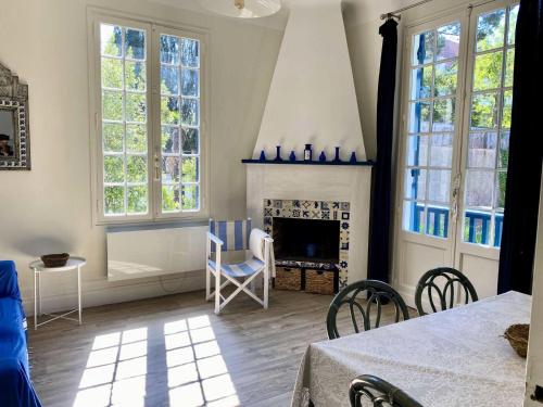 d'un salon avec une cheminée, des chaises et des fenêtres. dans l'établissement Résidence 385-arcachon - Appartement cosy pour famille, avec parking et balcons privés MAE-8884, à Arcachon