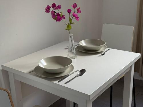 une table blanche avec deux bols et un vase avec des fleurs violettes dans l'établissement Les CARMES 1 G pour 2 pers - joli meublé et Wi-Fi, à Avignon