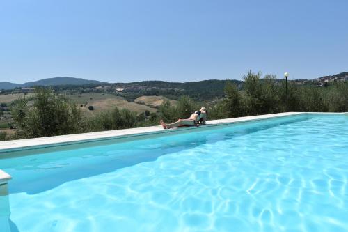 una donna seduta su una sedia accanto alla piscina di Hotel Del Buono Wellness & Medical Spa a Chianciano Terme