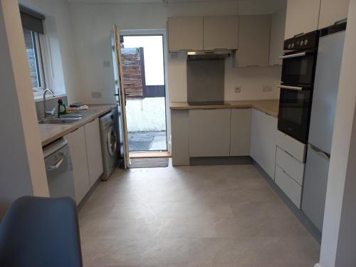 eine Küche mit weißen Schränken und einer Tür zu einem Hof in der Unterkunft Mourne Hikers' Cottage in Newcastle