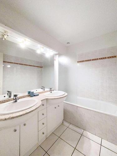 une salle de bain avec deux lavabos, une baignoire et un miroir dans l'établissement Résidence Eden Parc - Superbe villa avec piscine chauffée pour 8 personnes Lacanau Océan MAE-0631, à Lacanau
