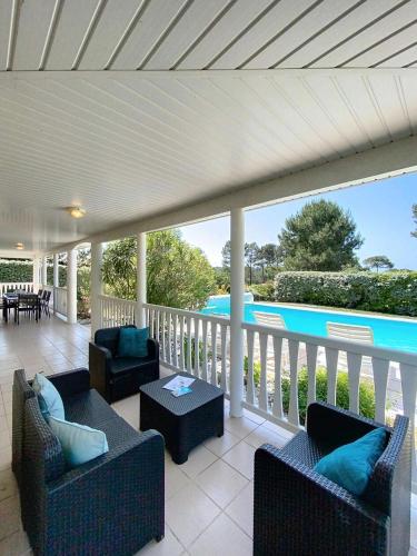 un porche couvert avec des canapés et une vue sur une piscine dans l'établissement Résidence Eden Parc - Superbe villa avec piscine chauffée pour 8 personnes Lacanau Océan MAE-0631, à Lacanau