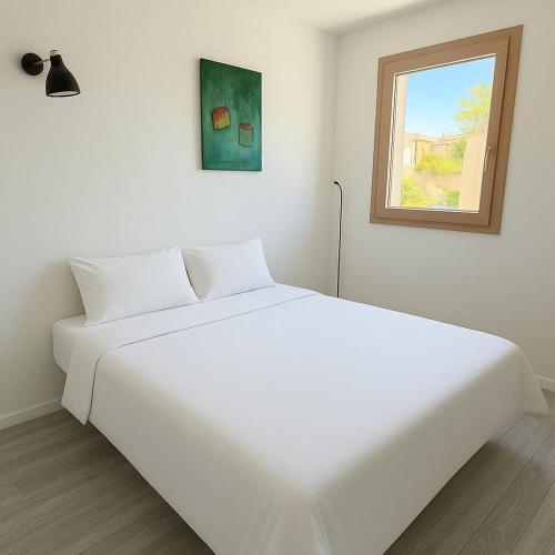 un lit blanc dans une chambre avec une fenêtre dans l'établissement Joli T2 lumineux, proche des plages, à Sète