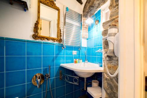 a blue tiled bathroom with a sink and a mirror at The Vernazza Main Plaza - Rooms & Suites in Vernazza