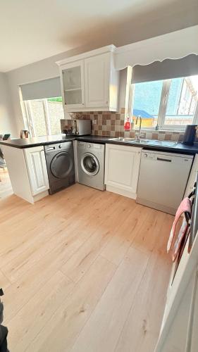 a kitchen with white cabinets and a washing machine at Gurteen Village Getaway in Cloonlaheen
