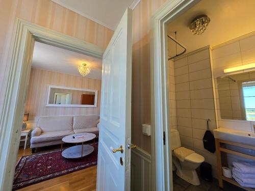a bathroom with a toilet and a couch in a room at Vänerport Lakefront Hotell in Mariestad
