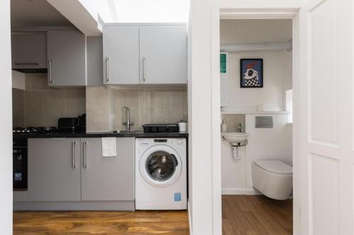 a kitchen with a washing machine and a toilet at Spacious London Oasis in Welling