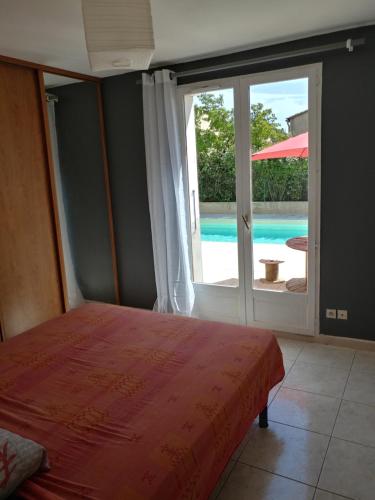 une chambre avec un lit et une vue sur une piscine dans l'établissement Villa avec grande piscine, à Nissan-lez-Enserune