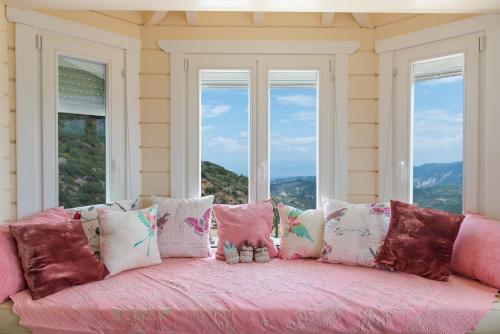 a pink couch with pillows in front of a window at Ktima Noosfera Wellness & Retreat Center in Nees Vrisoules