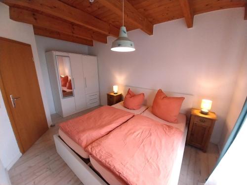 a bedroom with a bed with orange sheets and two lamps at Ferienhaus Dea in Krummhörn