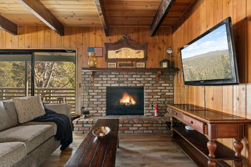 a living room with a fireplace and a tv at Pine Oaks Cabin in Lake Arrowhead