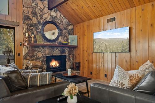 a living room with a fireplace and a stone wall at Pine Oaks Cabin in Lake Arrowhead