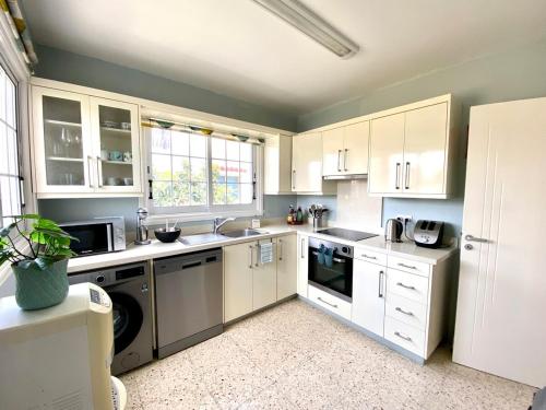 a kitchen with white cabinets and white appliances at Angelina retreat close to beach in Pyla
