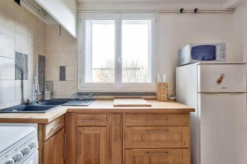une cuisine avec un réfrigérateur blanc et une fenêtre dans l'établissement Bel appartement St Michel, à Toulouse