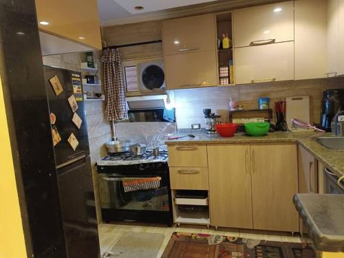 una cucina con mobili in legno e un frigorifero nero di بليله هاوس a Balīlā