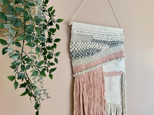 a crochet scarf hanging on a wall next to a plant at Private and lush tiny house 250m from beach in Egå