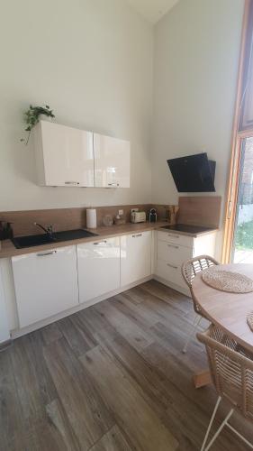a white kitchen with a sink and a table at Le 11 - Terrasse et jardin à 10 minutes à pieds du centre-ville in Strasbourg