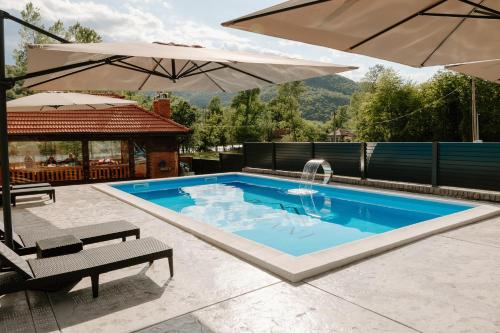 einen Pool mit Sonnenschirm und 2 Stühlen in der Unterkunft Apartmani Dejavu na Drini in Ljubovija