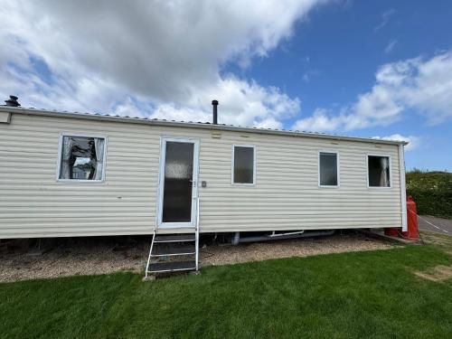 a white house with a ladder in a yard at Santos Caravan Beautiful Holiday Home in Clacton-on-Sea