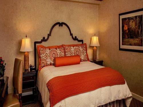 a bedroom with a bed with an orange pillow on it at Casa Munras Garden Hotel & Spa in Monterey
