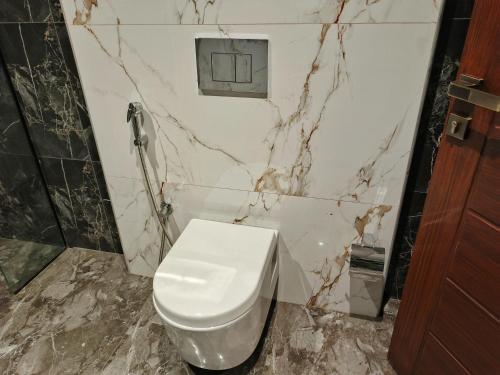a bathroom with a white toilet and marble walls at Executive Suite in Sambriāl