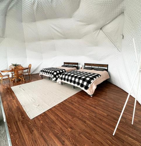 two beds in a room with white walls and wood floors at Chief Mountain Cabins in Carway
