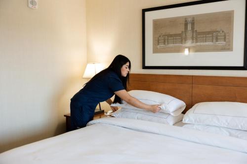 a woman putting pillows on a bed in a hotel room at Hilton Knoxville in Knoxville