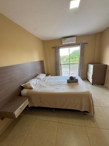 a bedroom with a large bed and a window at Apart Hotel BRIANA in Puerto Iguazú