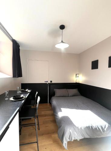 une chambre avec un lit et un bureau avec une chaise dans l'établissement Studio en rdc - hyper centre Dol de Bretagne, à Dol-de-Bretagne