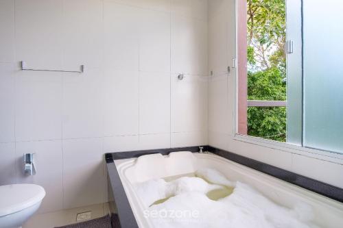 a bath tub in a bathroom with a window at Casa c/ Vista Lagoa e Churrasqueira CTM0000 in Siriú