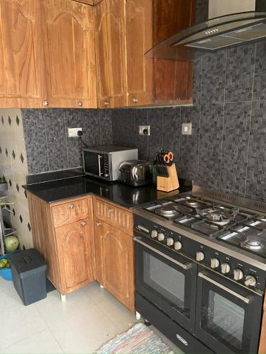 a kitchen with a black stove and wooden cabinets at The Manor in Lomé